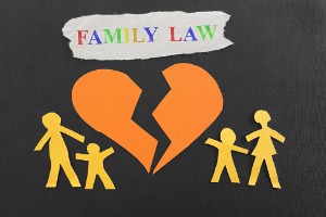 A paper cutout of a family on either side of a ripped heart, with family law written above it
