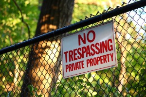 No Trespassing Sign on Wire Fence with Trees Behind