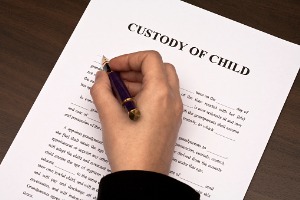 Parent signing papers for custody of child, with the help of a Child Custody Lawyer in East Peoria IL
