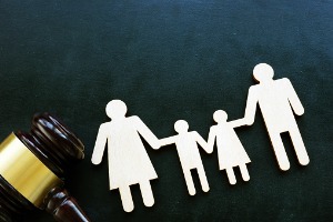 Paper family holding hands next to a gavel