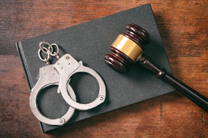 handcuffs laying on a black book next to a gavel representing Disorderly Conduct Peoria IL