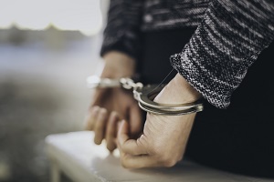 person in handcuffs behind their back sitting on a bench